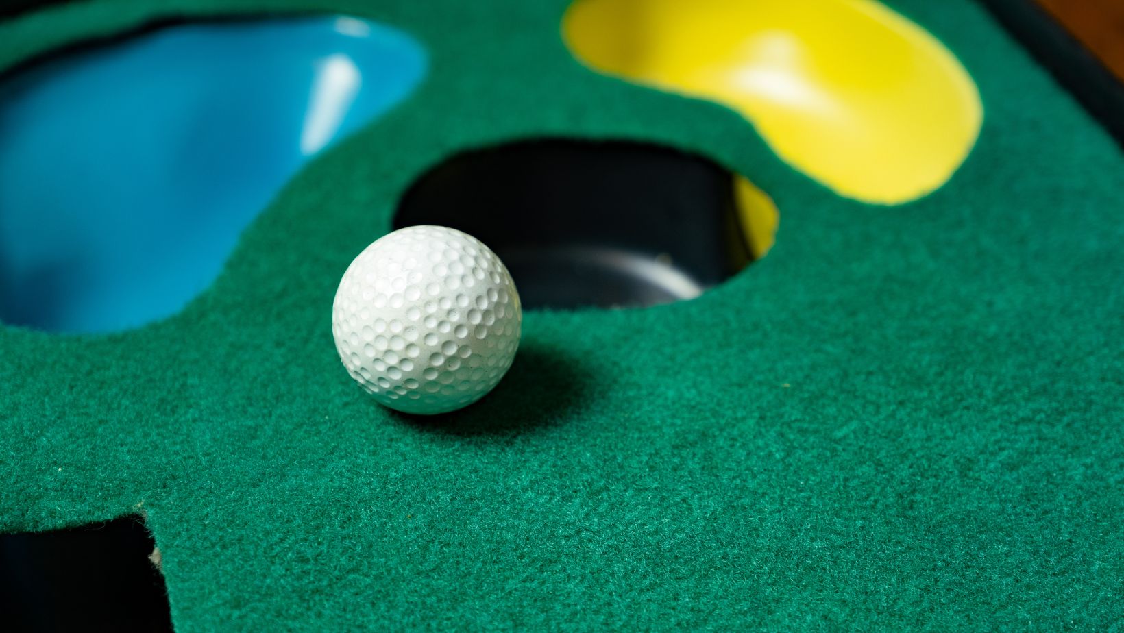 putting mat with golf ball and various holes