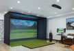 Indoor golf simulator setup in a room with a screen displaying a golf course using Carl's Place Premium Enclosure.