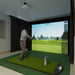 Person playing golf simulation game in a home setting with a screen displaying a golf course using Carl's Place Premium Enclosure.