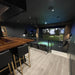 Indoor recreational room with a bar area and golf simulator using Carl's Place Premium Enclosure.