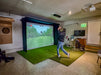 Person playing golf simulator in a room with a large Vanish Lite screen.
