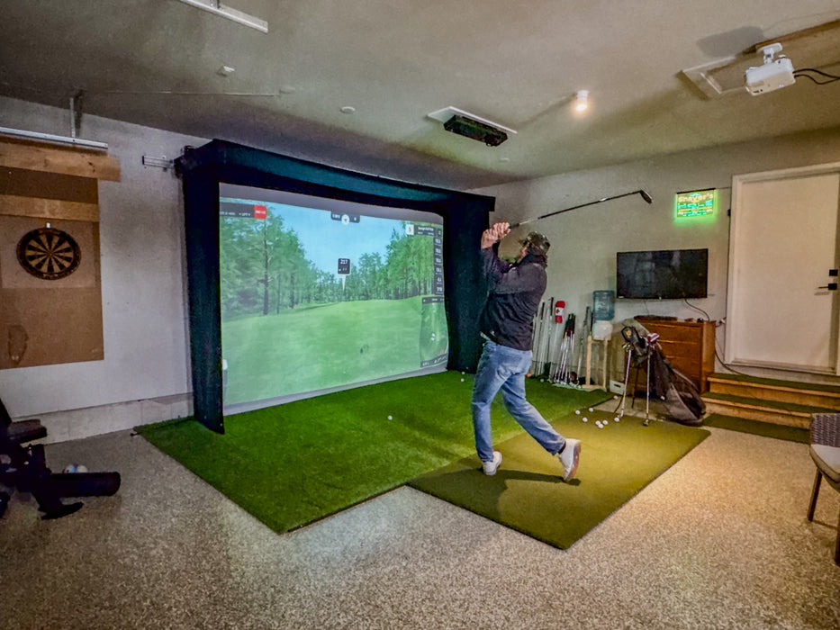 Person playing golf simulator in a room with a large Vanish Lite screen.